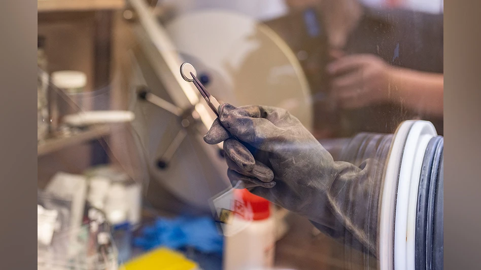 A UT Dallas researcher displays the battery after it is assembled in the glove box, a sealed container that is used when researchers work with hazardous and sensitive substances.